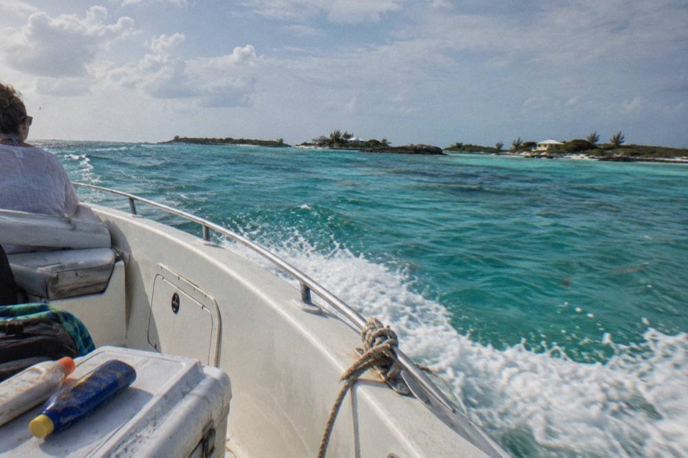 A powerboat cutting across open turquoise water toward a line of low cays