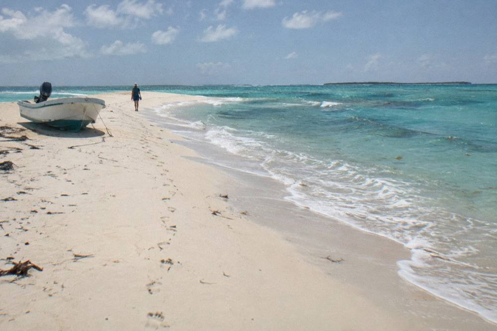 A white sandbar rising out of shallow turquoise water under a clear sky