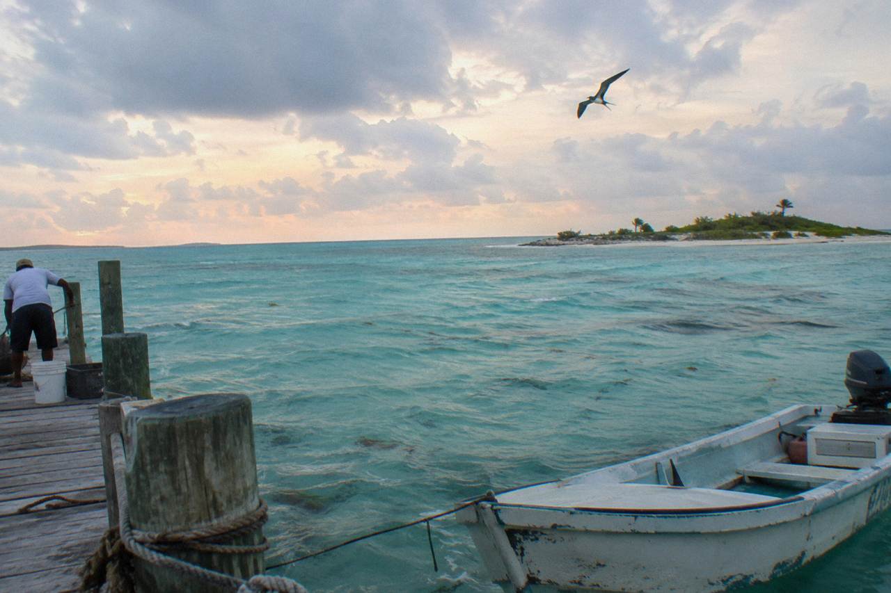 A calm turquoise bay in the Exuma Cays with a small sandy cay on the horizon