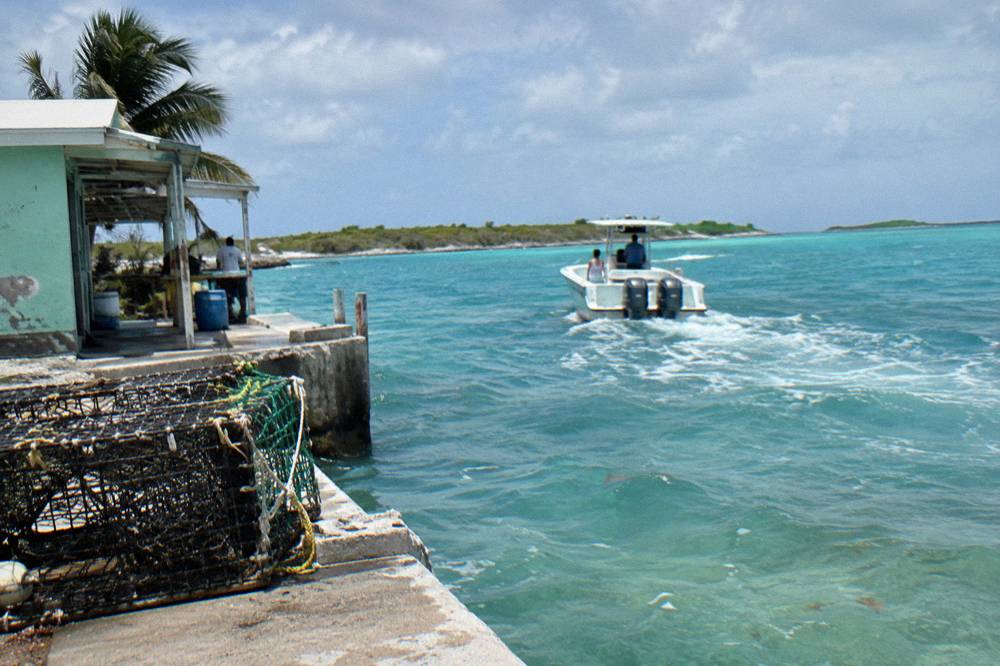 Powerboat cutting across open turquoise water toward low green cays
