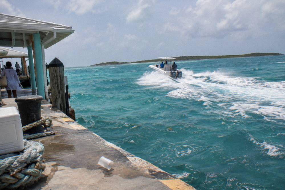 A speedboat cutting across open turquoise water toward low green cays