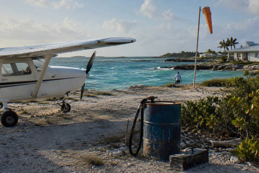 A light aircraft on a small airstrip beside turquoise island water