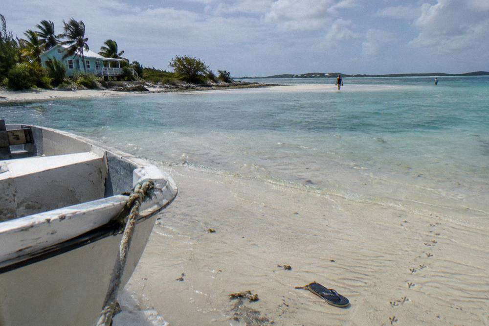 A calm turquoise bay with a sandbar exposed at low tide under a clear sky