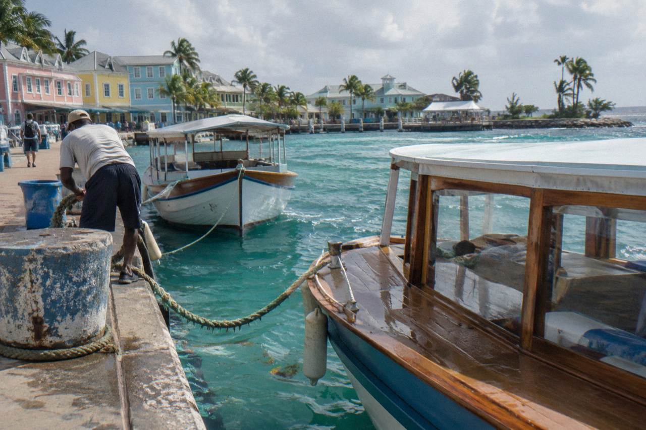Wooden tour boats moored in clear turquoise water beside a Nassau dock at morning