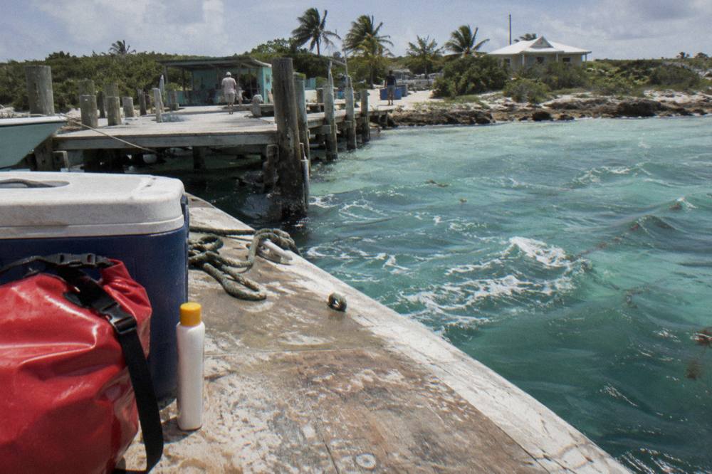 A dry bag and sunscreen packed on the deck of a boat beside a cooler