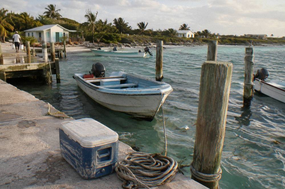 Boats tied at a small marina dock in clear shallow water